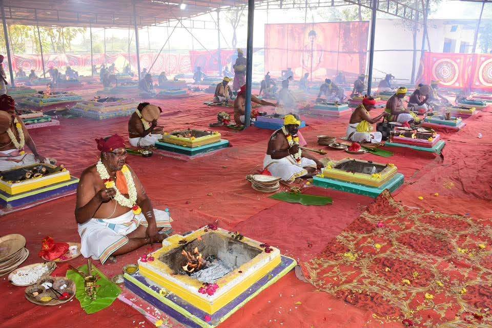 Priests seated at rows of decorated homa kunds during a Vedic fire ceremony