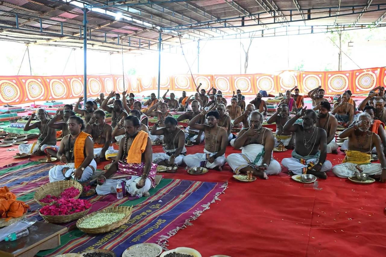 Priests offering rice and flowers together during a Vedic yagna