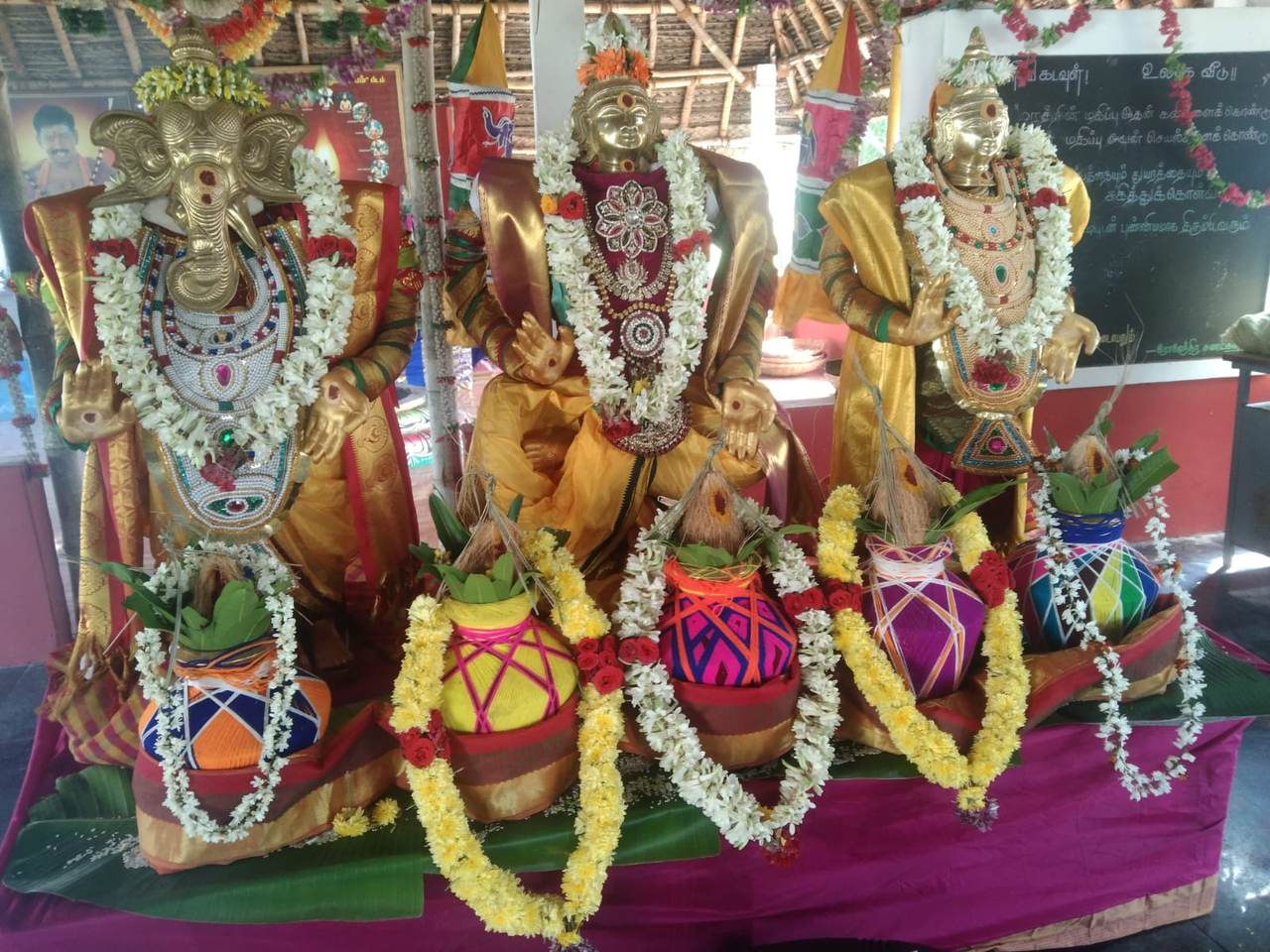 Golden deities adorned with garlands and kalash pots