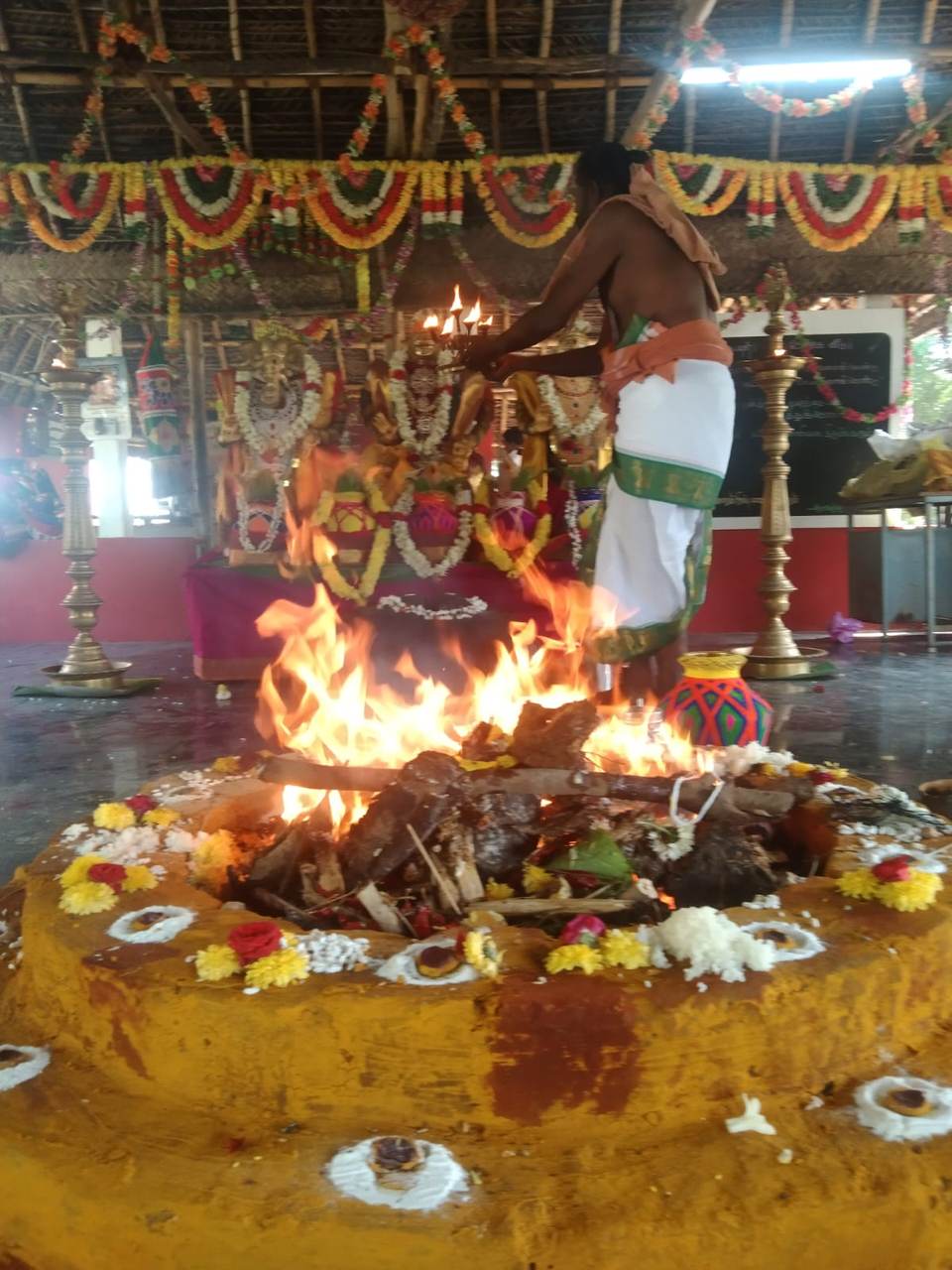 Priest performing aarti with a lit lamp over the sacred fire