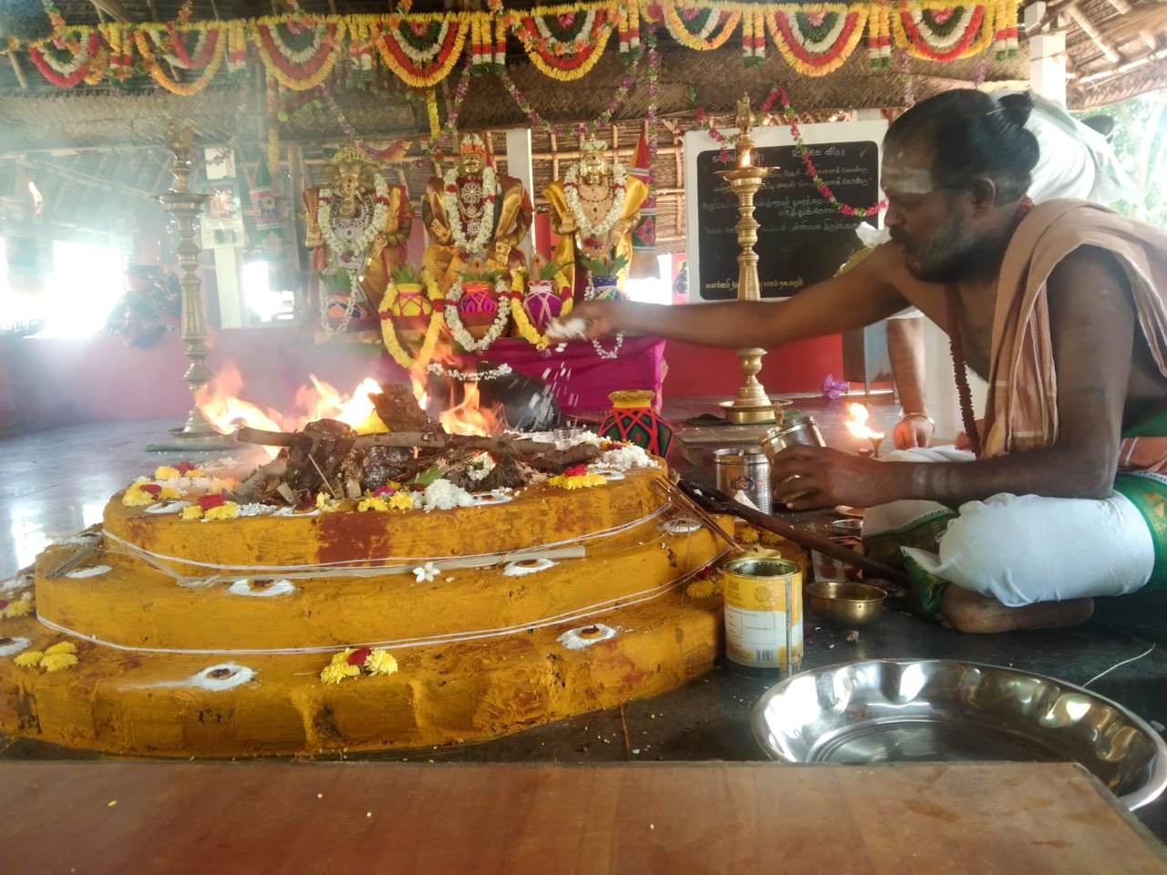 Priest sprinkling sacred offerings over the fire during the ritual